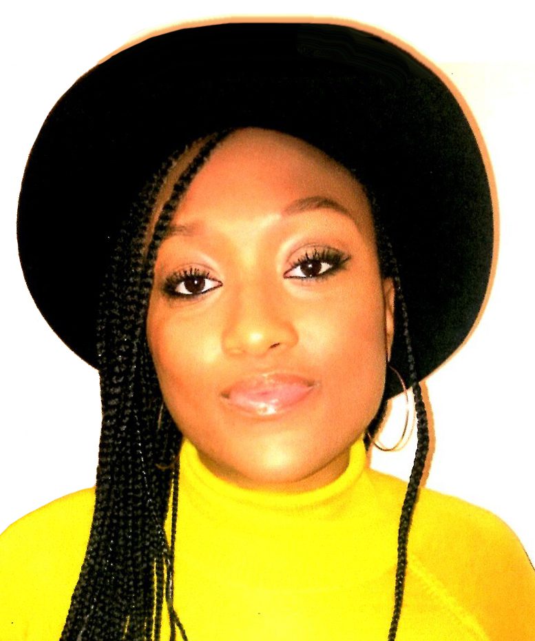 A woman with long black braids wearing a yellow top.