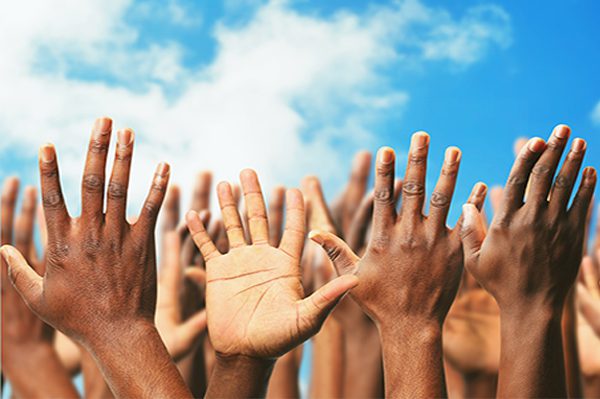 A group of people raising their hands in the air.